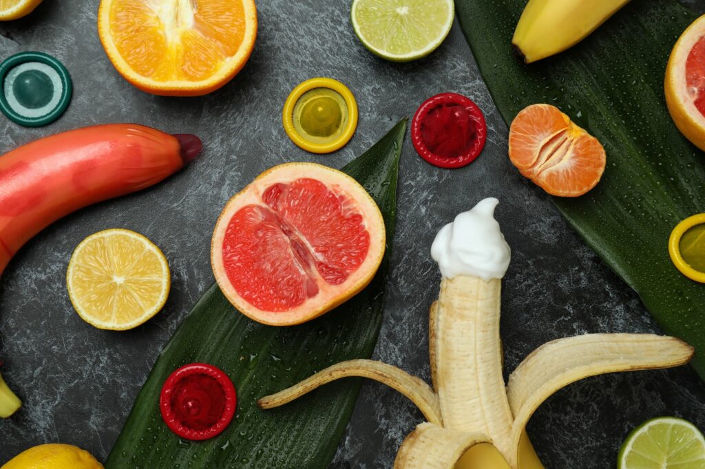 Sex concept with fruits and condoms on dark background