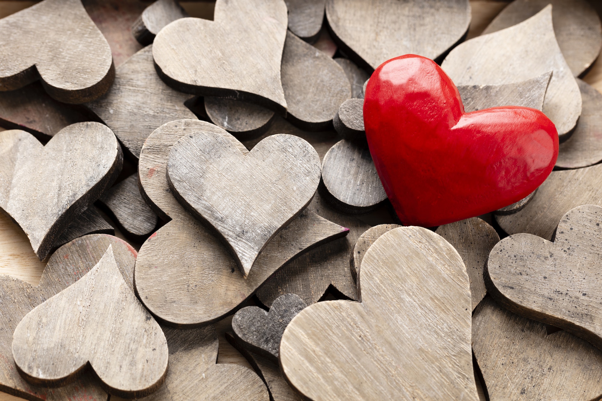Wooden hearts, one red heart on the heart background.